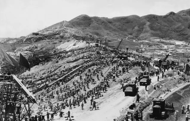 1月1日：距北京50公里，长城附近。一座水坝的建设工地全景。这是毛泽东在其“大跃进”政策下所推动的工程。这座水坝长600米、高30米、宽160米，旨在蓄积8000万吨水量，并提供2万千瓦的电力。这项浩大工程动用了40万中国民工参与建设。